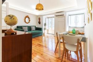sala de estar con mesa y sofá verde en Castelo Premium by Homing, en Lisboa