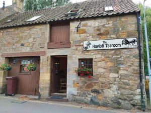 - un bâtiment en pierre avec un panneau à l'avant dans l'établissement The Hayloft, à Falkland