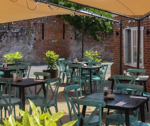 an outdoor patio with tables and chairs and a brick wall at The Kings Head in Whiteparish