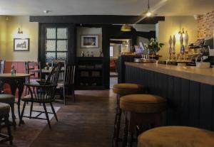 un restaurante con bar y algunas sillas y mesas en The Kings Head en Whiteparish