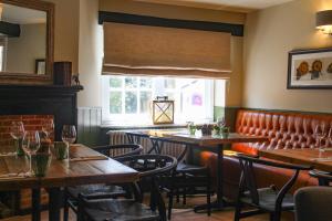 a restaurant with wooden tables and chairs and a window at The Kings Head in Whiteparish