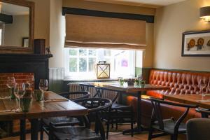 un restaurante con mesas y sillas de madera y una ventana en The Kings Head en Whiteparish