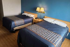 a hotel room with two beds and a blue wall at Travelodge by Wyndham Stockton in Stockton