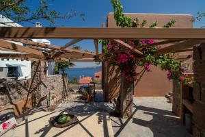 a wooden pergola with flowers and a view of the ocean at Absolute Perdika Aegina in Perdika