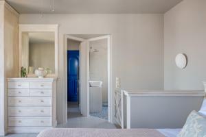 a white bedroom with a white dresser and a bathroom at Absolute Perdika Aegina in Perdika