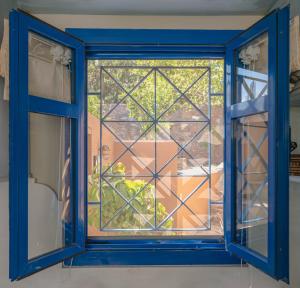 a blue window with a view of a garden at Absolute Perdika Aegina in Perdika