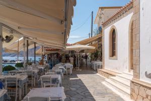 a restaurant with tables and chairs and umbrellas on a street at Absolute Perdika Aegina in Perdika