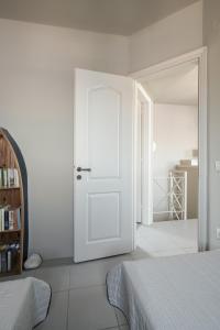 a white room with a white door and a bedroom at Absolute Perdika Aegina in Perdika