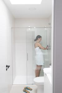 Una mujer parada en una ducha en un baño en Hostel Villa Miguela, en Santander