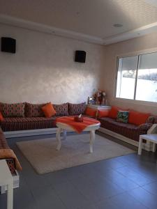 a living room with couches and a table at Sidi Rahal Villa avec piscine à 5min de la plage in Dar Hamida