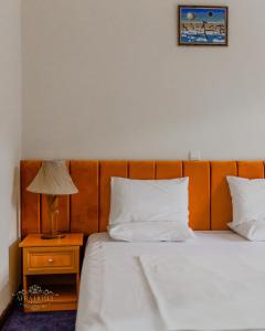 a bed with white sheets and a lamp on a night stand at Afra Oghuz Mountain Resort Hotel in Oğuz