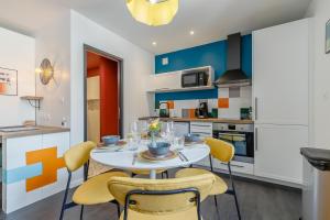a kitchen and dining room with a white table and yellow chairs at Mon Petit Sejour Lucon in Luçon +6 photos