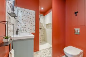 a bathroom with orange walls and a toilet and a sink at Mon Petit Sejour Lucon in Luçon