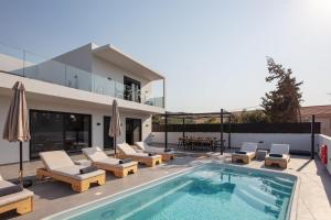 a swimming pool with lounge chairs and a house at Horizon Luxury Villa in Chania Town