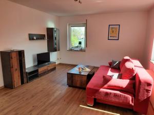a living room with a red couch and a tv at Enscher Stübchen Ferienwohnung Rudolf in Ensch