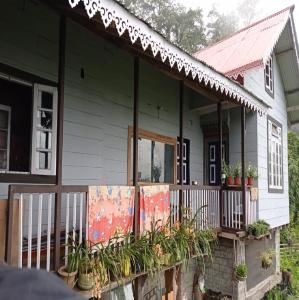 Una casa con un porche con plantas. en Rinzeebong Homestay by StayApart, en Mangan