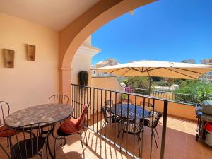 einen Balkon mit Tischen, Stühlen und einem Sonnenschirm in der Unterkunft Villa La Dorada Burriana Casasol in Nerja