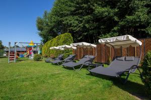 a row of lawn chairs with umbrellas in a park at Apartamenty i pokoje Montana in Kudowa-Zdrój