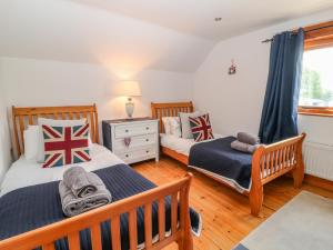 a bedroom with two beds and a window at Rosies Barn in Bideford