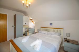 a bedroom with a large white bed with towels on it at 7 Harbour Reach in Weymouth