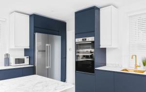 a kitchen with blue cabinets and a stainless steel refrigerator at Stunning 2 bedroom apartment in fantastic location in Bristol