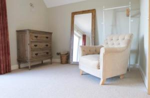 sala de estar con silla blanca y cómoda en The Silver Birch Cottage - Greentrees Estate, en Haywards Heath