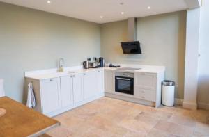 a kitchen with white cabinets and a tv on the wall at The Silver Birch Cottage - Greentrees Estate in Haywards Heath