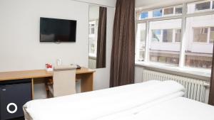 a hotel room with a bed and a desk and window at Center Hotels Klopp in Reykjavík