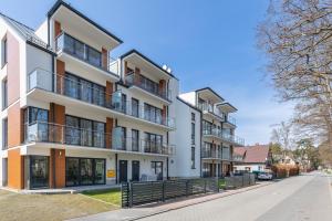 un edificio de apartamentos con balcones en una calle en Little Laguna Apartments Sauna & Parking by Renters, en Międzywodzie