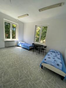 a bedroom with two beds and a table and windows at Pokoje Fregata Świnoujście in Świnoujście