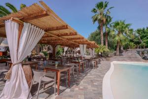 een restaurant met tafels en parasols naast een zwembad bij Il Monastero in Geremèas