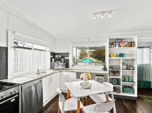 a kitchen with white cabinets and a table and chairs at Coastal Vibes - Walk to beach, Marina, Cafes and Pubs in Shellharbour