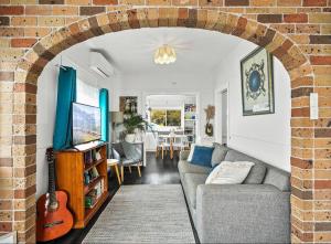 an archway in a living room with a couch and a guitar at Coastal Vibes - Walk to beach, Marina, Cafes and Pubs in Shellharbour