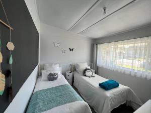 two beds in a room with white walls at Coastal Vibes - Walk to beach, Marina, Cafes and Pubs in Shellharbour