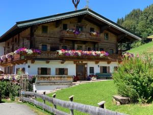 une grande maison en bois avec des fleurs sur le toit dans l'établissement Reitstall Henntalhof, à Kitzbühel