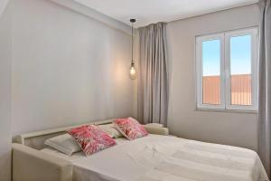 1 dormitorio con 1 cama con almohadas rosas y blancas en Casa Rebelo da Silva, en Faro