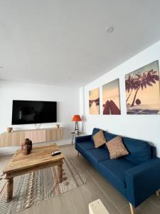 ein Wohnzimmer mit einem blauen Sofa und einem Tisch in der Unterkunft Apartamentos Buganvilla Roquetas de Mar in Roquetas de Mar