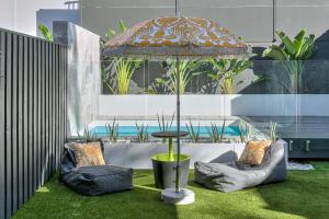 une terrasse avec 2 chaises et une table avec un parasol dans l'établissement Grandview Villa Kingscliff - Oceanview Tri-level Villa by uHoliday, à Kingscliff