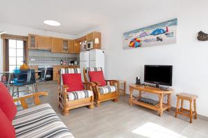 a living room with chairs and a tv and a kitchen at Puerto Chico 9 in Playa Blanca