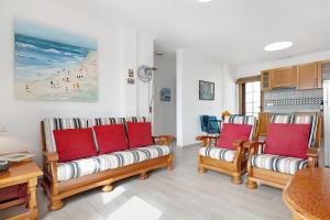 una sala de estar con 3 sofás con almohadas rojas en Puerto Chico 9, en Playa Blanca