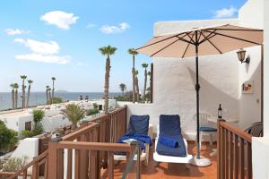 a balcony with chairs and an umbrella and the ocean at Puerto Chico 9 in Playa Blanca