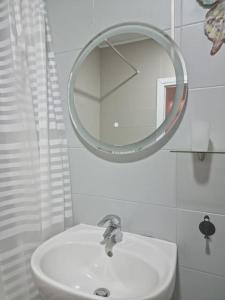 ein Badezimmer mit einem weißen Waschbecken und einem Spiegel in der Unterkunft AryaHome in Bistriţa