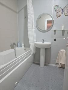 a white bathroom with a sink and a mirror at AryaHome in Bistriţa