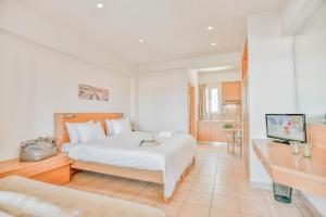 a white bedroom with a bed and a desk at Anatoli Apartments in Agia Pelagia