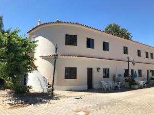 a large white building with a table and chairs at Casas da Praia in Manta Rota