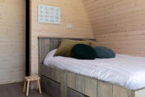 1 cama en una cabaña de madera con 2 almohadas en Pod huisje met hottub, en Dokkum