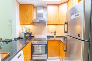 a kitchen with wooden cabinets and a stainless steel refrigerator at Fully equipped studio near to metro - HRI in Dubai