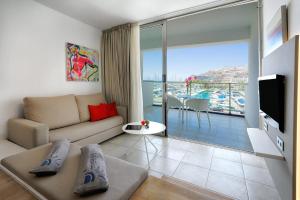 a living room with a couch and a large window at Morasol Suites in Puerto Rico de Gran Canaria