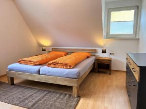 1 dormitorio con 1 cama con almohadas de color naranja y ventana en Ferienwohnung Kinzigblick *NEU* für Familien im Schwarzwald Kinzigtal, en Schenkenzell