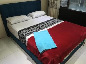 a bed with a red white and blue blanket at Bhan Towers Apartment in Suva